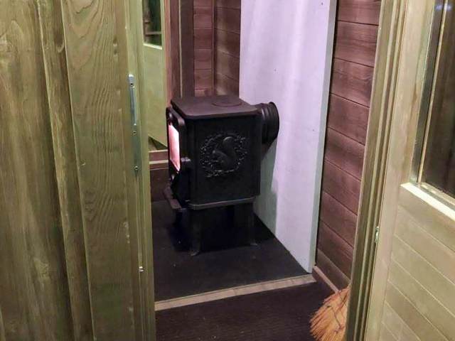 Печь-камин у входа внутри дома на дереве